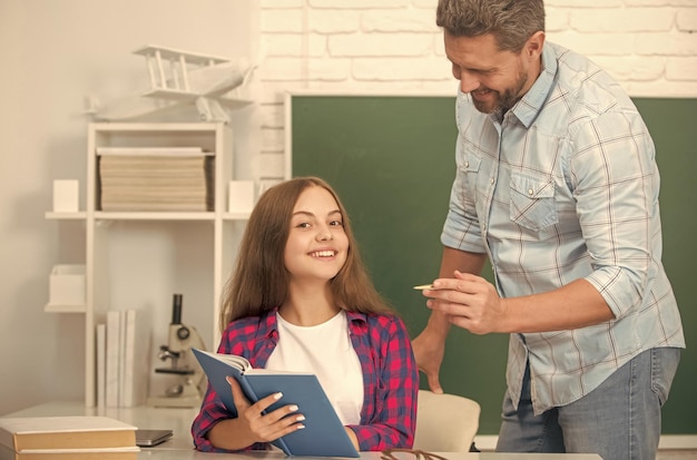 Foto felice padre e figlio studiano a scuola con il libro sull'istruzione di fondo della lavagna