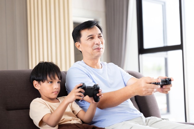 Felice padre papà e figlio giocano alla stazione di videogiochi con il gioco di controllo tramite la tecnologia del joystick remoto per l'attività di intrattenimento familiare durante il fine settimana