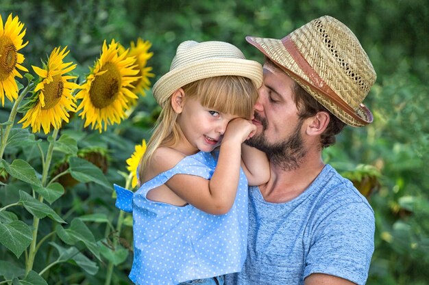 Happy father and daughter are hugging in the field of sunflowers