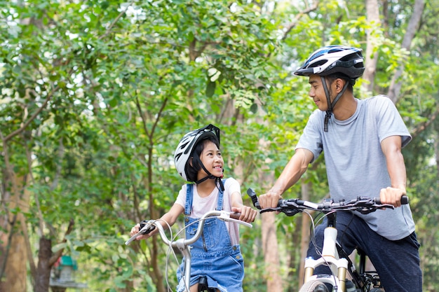 Счастливый отец и дочь на велосипеде в парке