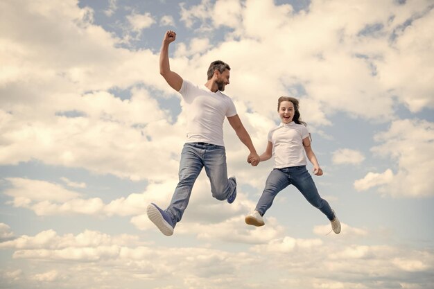 幸せな父と娘が空にジャンプします