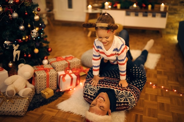 Happy father and daughter playing in the living room on Christmas eve