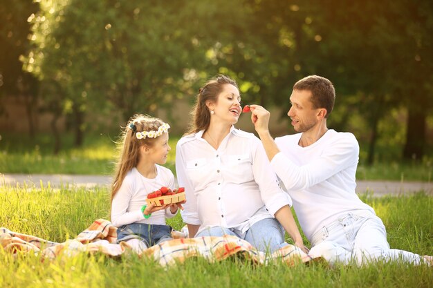 Happy father of a daughter and a pregnant mom at a picnic