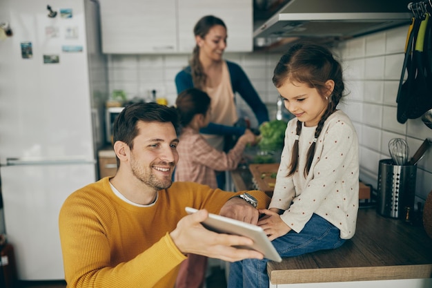 Happy father and daughter using touchpad in the kitchen