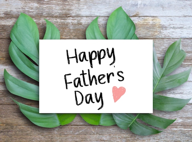 happy father day letters written on white paper placed on leaves and wooden table