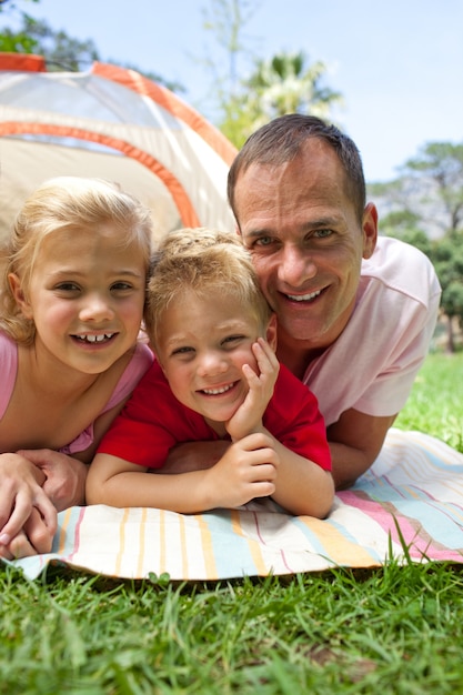 Foto padre felice e i suoi figli sdraiato sull'erba