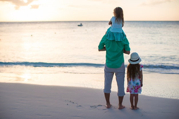 Happy father and his cute little daughters at beach