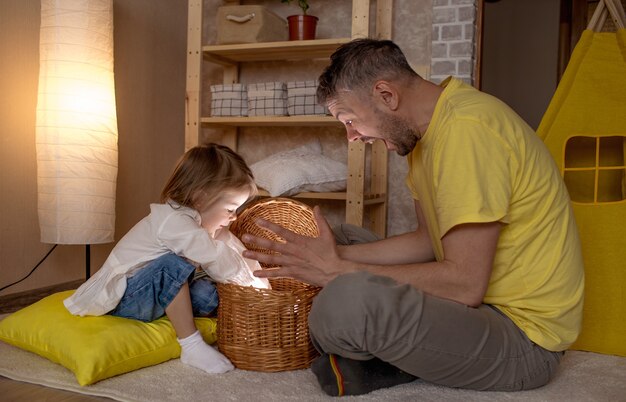 A happy father and his little daughter are surprised to open a wicker surprise box. happy mood.