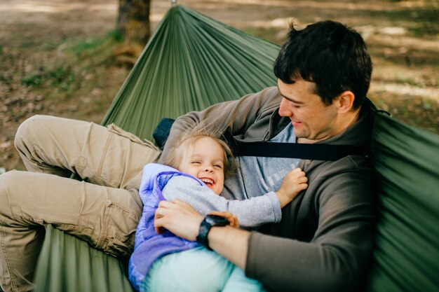 happy father and his little daughter relaxing in hammock at nature