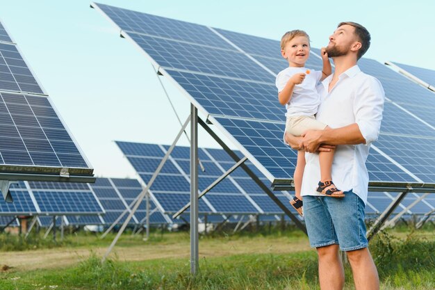 Happy father and his little son are walking near the solar panels the concept of green energy