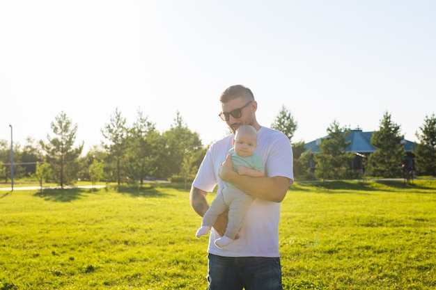 Happy father holding baby son on nature concept of happy family fathers day and child