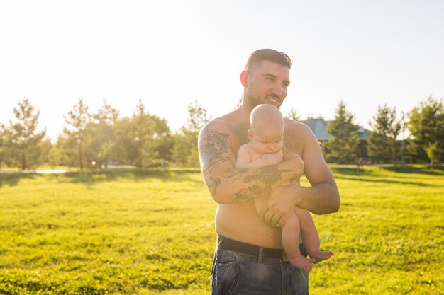 Padre felice che tiene in braccio il figlio del bambino sul concetto di natura di felice festa del papà e bambino in famiglia