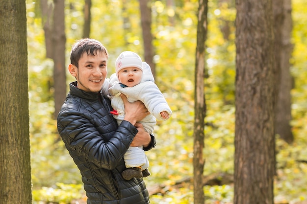 Happy father holds the little daughter in her arms among the trees