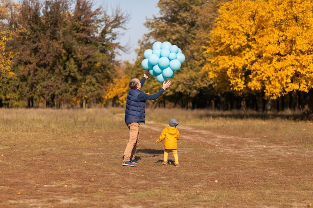 행복한 아버지는 가을 공원에서 아이와 함께 하루를 보내고 풍선을 가지고 놀고 있다