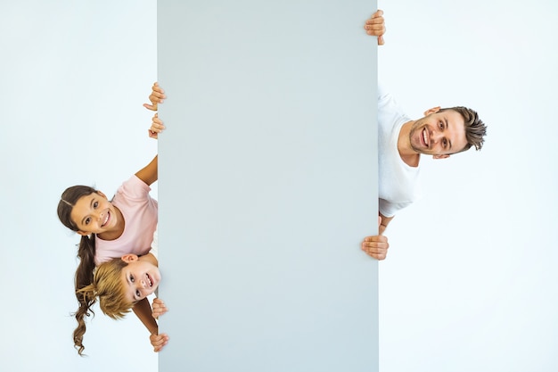 The happy father and kids stand behind the wall