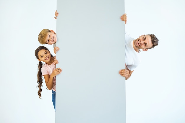 The happy father and kids stand behind the wall