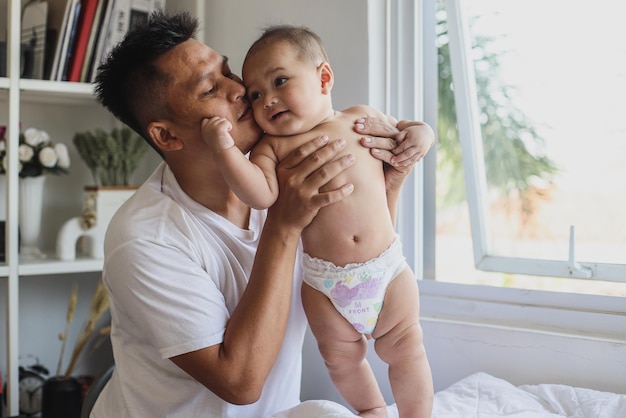 Happy father kiss adorable baby cheeks while playing at home