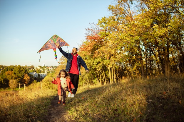 Happy father and little cute daughter walking down the forest path in autumn sunny day