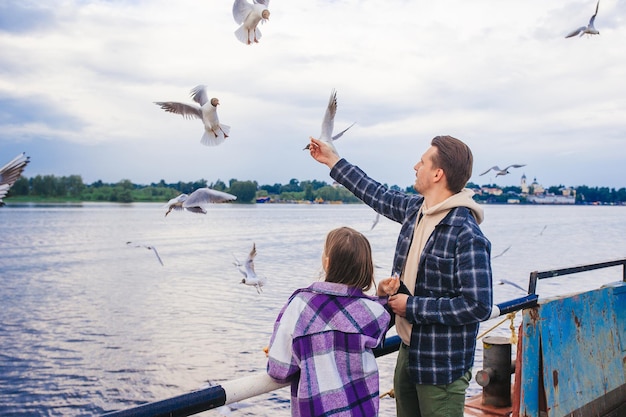 Happy father and little girl feed seagulls