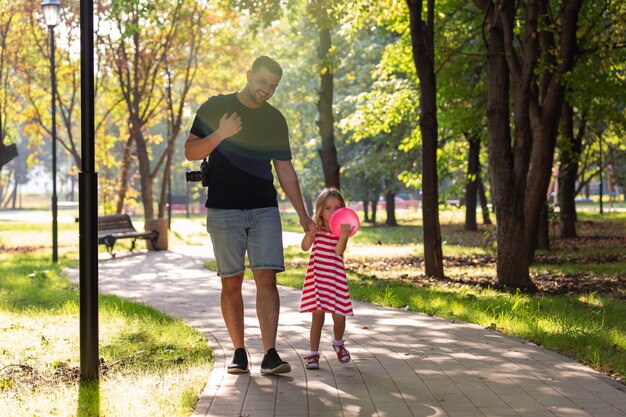 幸せな父と夏の公園で手をつないで歩く少女