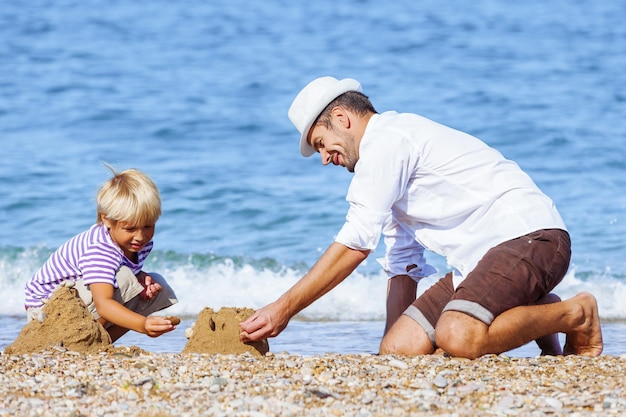 Photo happy father and little son play at sunny beach