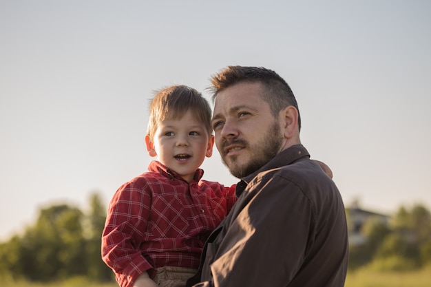 happy father and little son rest on the field of feather-grass