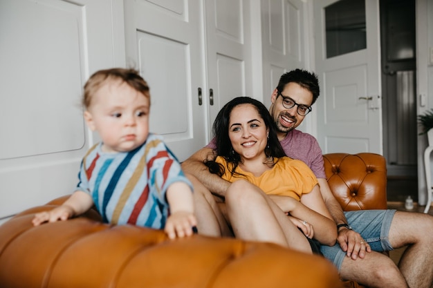 happy father and mother with son on sofa at home