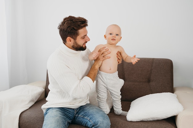 Happy father playing at home with baby