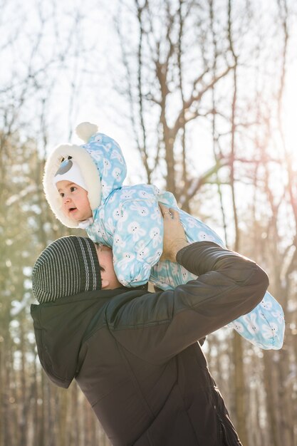 冬の自然の中で小さな子供息子の男の子と遊んで幸せな父。