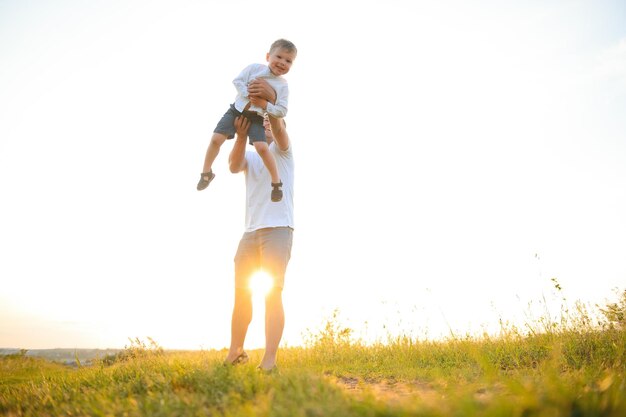 Happy father playing with son on sunset background The concept of father's day