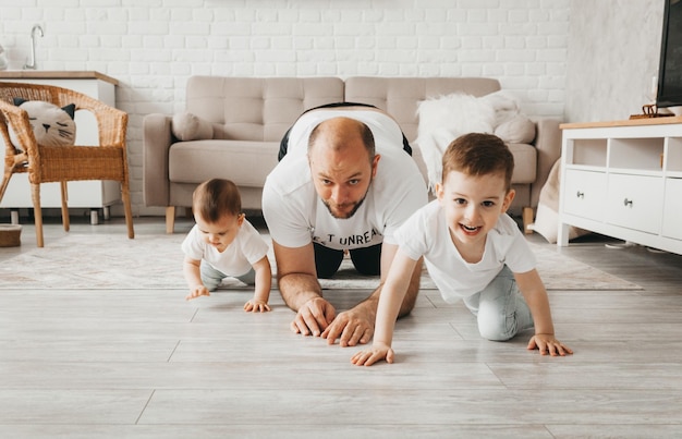 Счастливый отец играет в догонялки с детьми на полу Отец с детьми ползает по полу