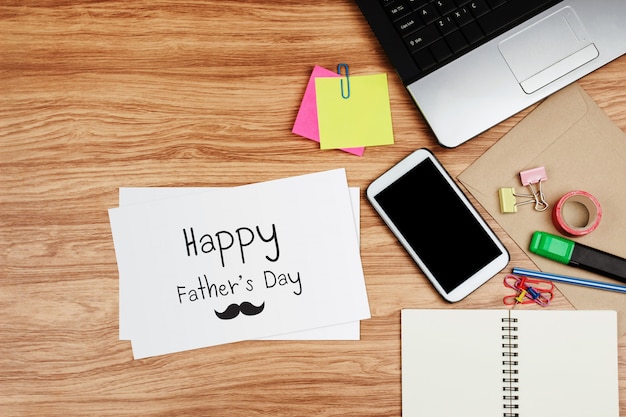 Foto scheda felice di festa del papà con gli articoli per ufficio sullo scrittorio di legno