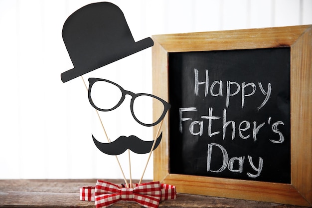 Happy Father's Day inscriptie op bord met vlinderdas op houten tafel