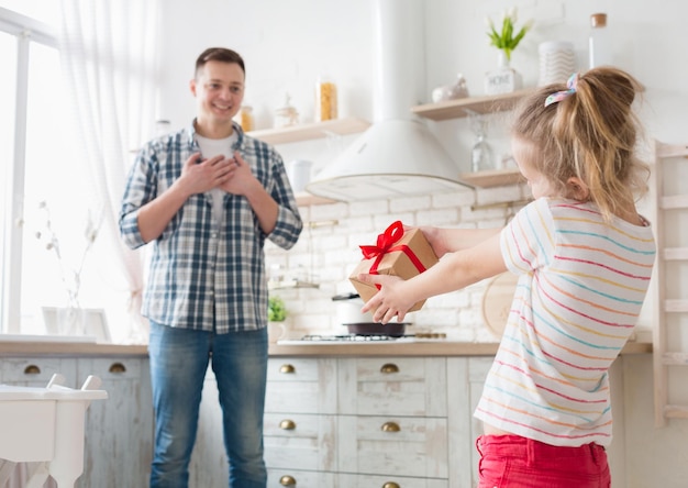 Happy father's day. Little daughter congratulating dad and giving gift box, copy space