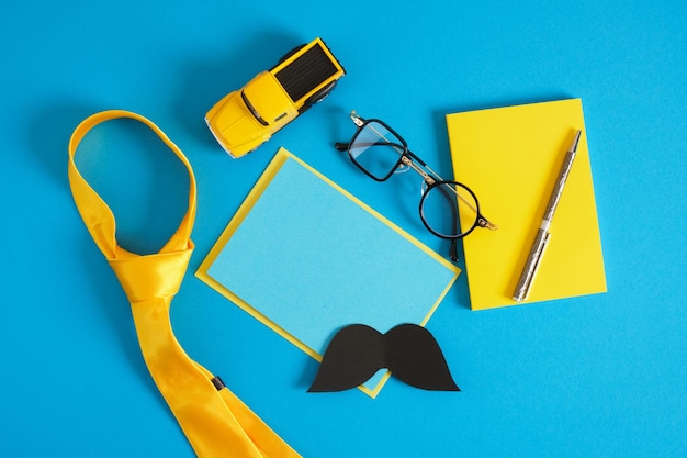 Happy father's day mockup notebook creative glasses cars tie on a blue background items in yellow colors