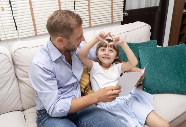 Happy Father's day Schattig meisje maakt hart met handen voor haar vader thuis in de woonkamer