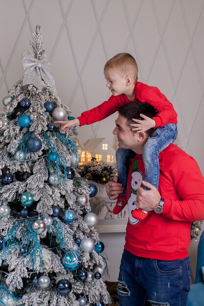 Happy Father and son enjoying decorating Christmas tree with Christmas balls