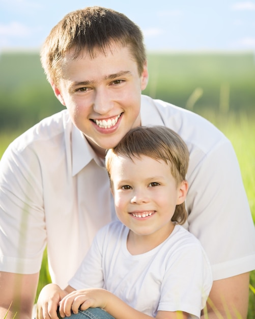 Photo happy father and son having fun outdoors in spring green field against blue sky background