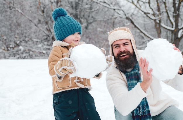 凍るようなウィンターパークの冬の父と雪の冬の家族で雪だるまを作る幸せな父と息子...