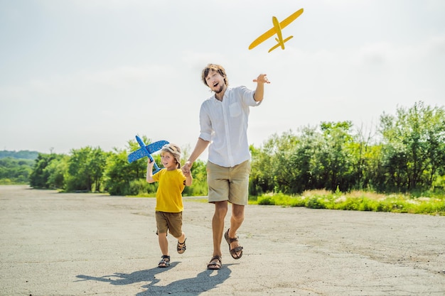 Happy father and son playing with toy airplane against old runway background Traveling with kids concept