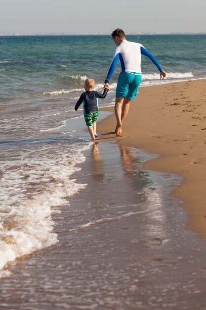 happy father and son run barefoot on the beach spend time together lifestyle family cyprus copy space