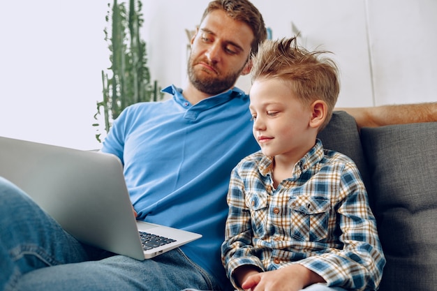 Happy Father and son sitting on couch and watching something on laptop