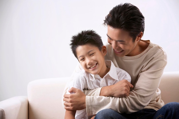 happy father and son sitting on sofa against white background