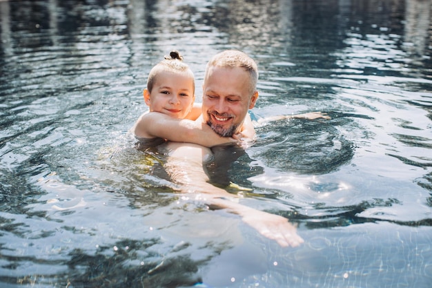 Happy father and son spend time together swimming in the swimming pool