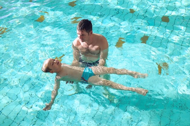 Happy father and son swimming lesson in pool child learning swim family parenthood health sport