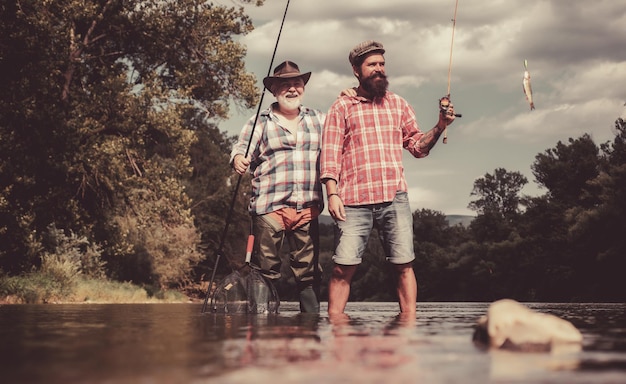 Felice padre e figlio insieme la pesca in un giorno d'estate sotto il bel cielo sul fiume pesca a mosca mosca