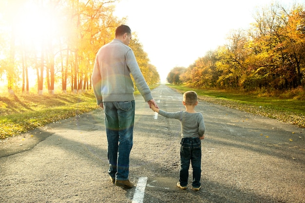 幸せな父と息子が自然の秋を歩く