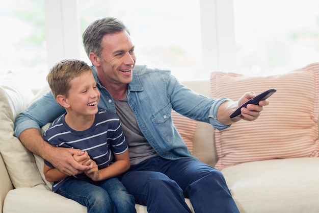 Happy father and son watching tv in living room