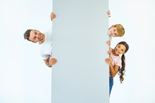 The happy father with a boy and a girl stand behind the wall