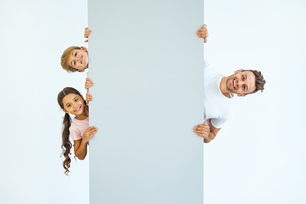 The happy father with a boy and a girl stand behind the wall